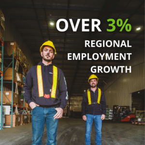 Two adults stand wearing construction gear in a warehouse, boxes can be seen on the left side and a forklift in thebackground on the right overlayed text reading "Over 3% regional employment growth"