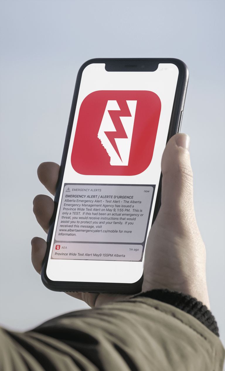 Cell phone with an Alberta Emergency Alert warning on screen.