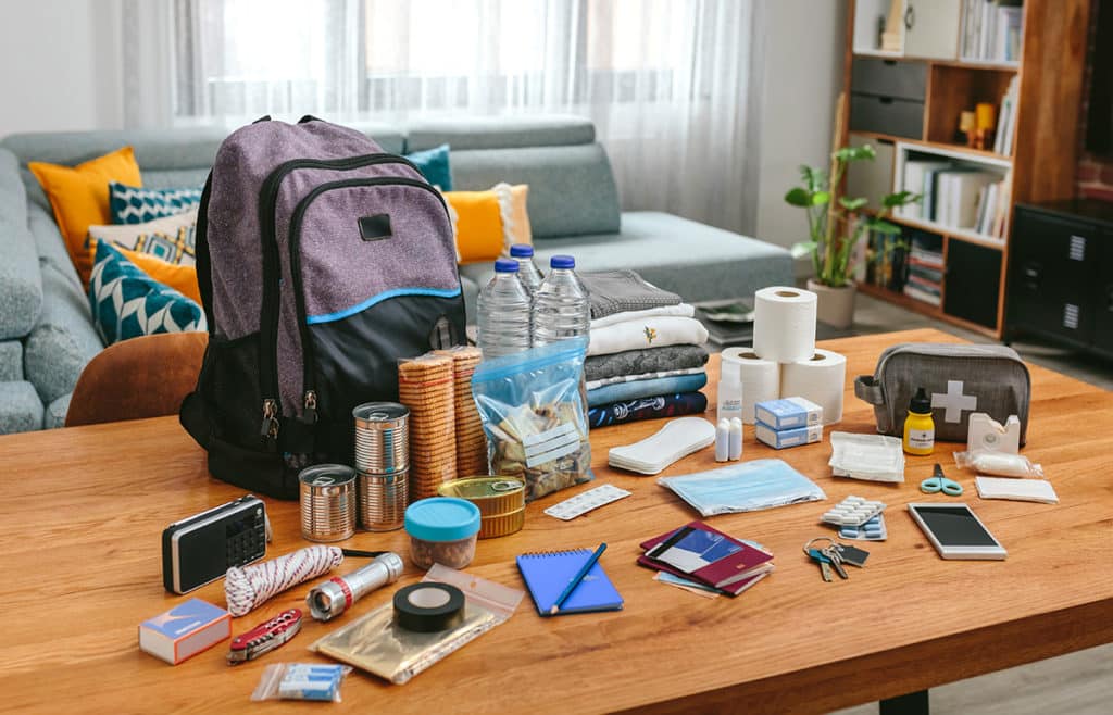 Emergency backpack equipment organized on the table in the living room.