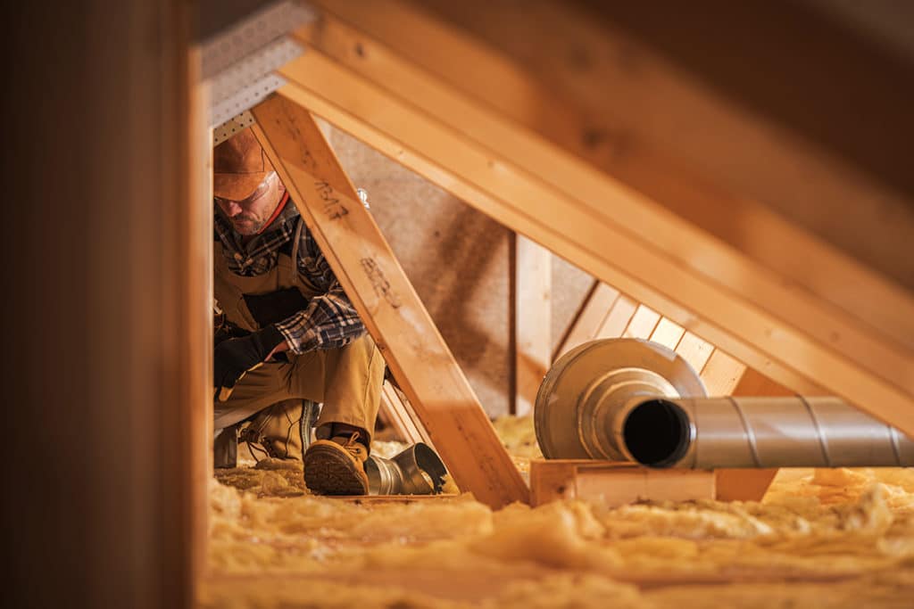 HVAC worker working in an attic.