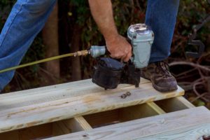 Person using a nailer to secure deck boards to frame for a deck.