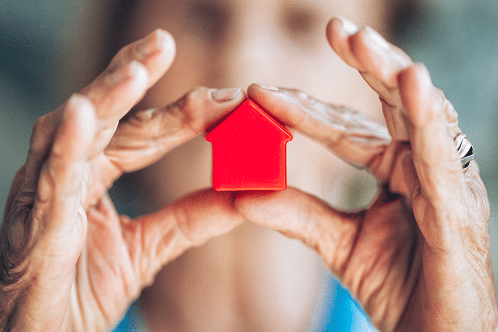 Two hands holding a red toy house.