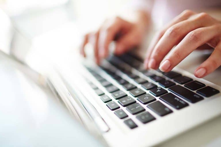 Person typing on a laptop keyboard.