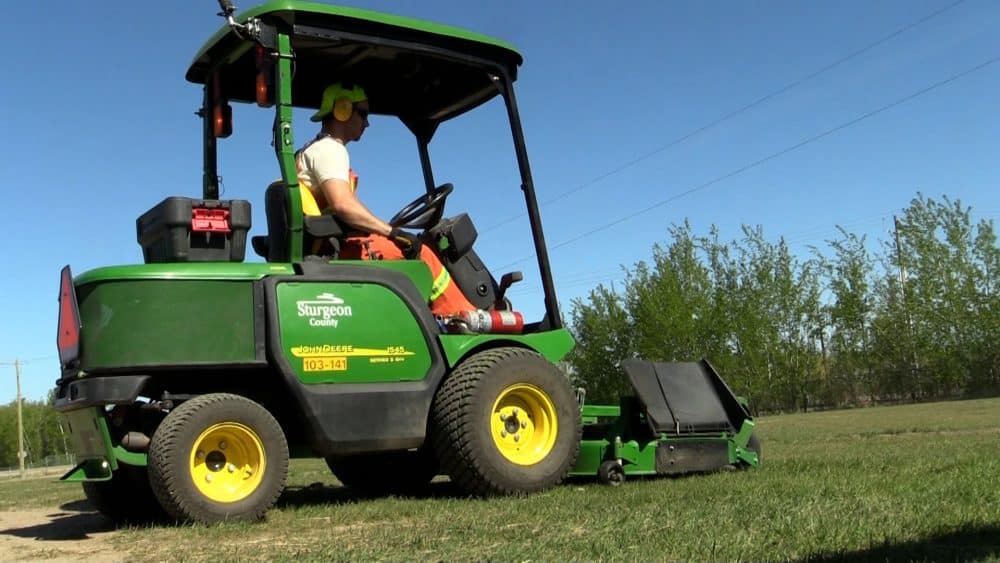 Sturgeon County employee on a ride-on tractor mowing grass